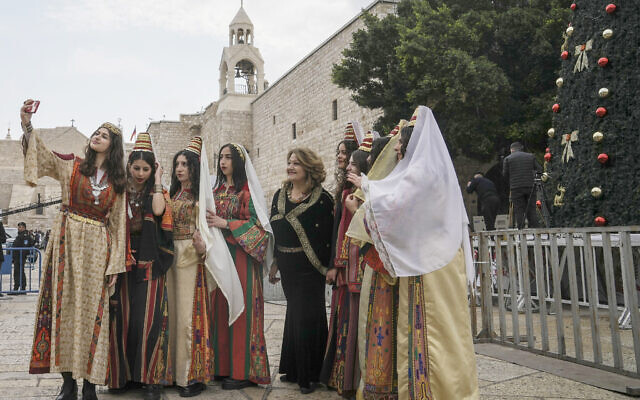 Women pose for a photo as they visit the Church of the Nativity, traditionally believed to be the birthplace of Jesus Christ, in the West Bank town of Bethlehem, December 24, 2022. (AP Photo/Mahmoud Illean)