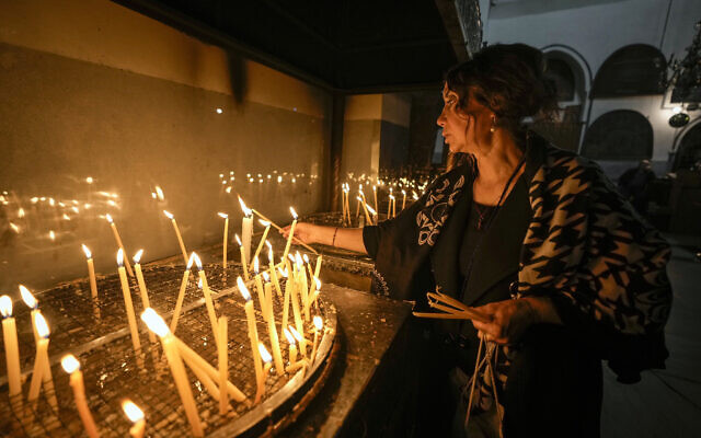 A woman lights candles inside the Church of the Nativity, traditionally believed to be the birthplace of Jesus Christ, in the West Bank town of Bethlehem, December 24, 2022. (AP Photo/Majdi Mohammed)