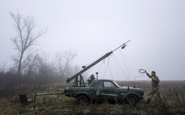 Ukrainian servicemen from 127 brigade prepare a telescopic tower with a remote camera installed on a Soviet car "Volga" that was recast to observe and correct fire on the front line near Kharkiv, Ukraine, December 25, 2022. (AP Photo/Evgeniy Maloletka)
