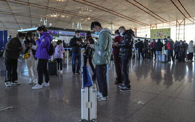 Masked travellers use their smartphones to fill in their health declaration after checking in at the international flight check in counter at the Beijing Capital International Airport in Beijing, Thursday, Dec. 29, 2022. (AP Photo/Andy Wong)