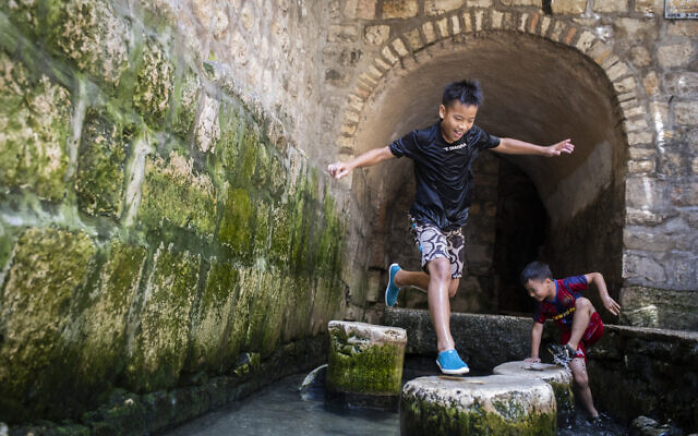 Young boys from Taiwan play in the water of the Siloam Pool after walking through Hezekiah's Tunnel during their visit to the City of David National Park, on July 28, 2019. (Hadas Parush/Flash90)