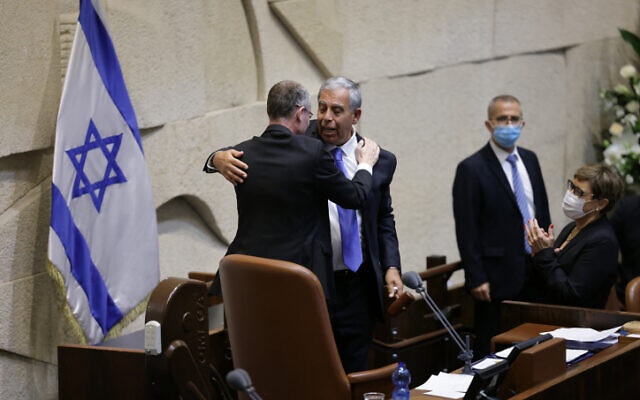 Mickey Levy embraces Yariv Levin in the Knesset on June 13, 2021. (Olivier Fitoussi/FLASH90)