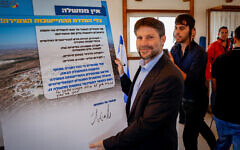 Bezalel Smotrich holding a sign calling for the authorization of new settlements during a visit to the West Bank on October 26, 2022. (Gershon Elinson/Flash90)