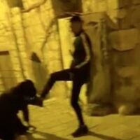 An ultra-Orthodox man bends down and kisses the foot of a Palestinian teen in the Old City of Jerusalem; two Palestinian teens were arrested over the incident on December 1, 2022. (Screen capture/Twitter)
