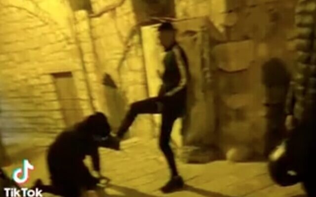 An ultra-Orthodox man bends down and kisses the foot of a Palestinian teen in the Old City of East Jerusalem in what led to the latter's arrest on December 1, 2022. (Screen capture/Twitter)