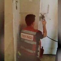 This screenshot of video released by police shows a first responder breaking the lock on a shelter in the central city of Lod, where two Palestinian teenagers illegally in Israel were held against their will. (Screen capture from Twitter, used in accordance with Clause 27a of the Copyright Law)