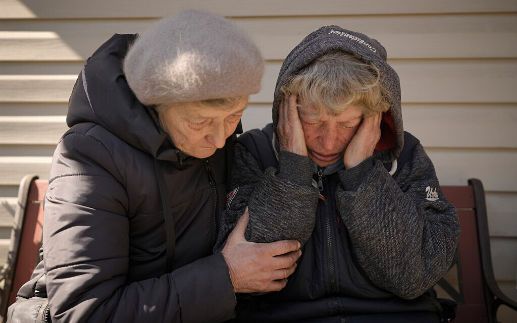 A neighbor comforts Natalia Vlasenko, whose husband, Pavlo Vlasenko, and grandson, Dmytro Chaplyhin, were killed by Russian forces, as she cries in her garden in Bucha, Ukraine, April 4, 2022. (AP Photo/Vadim Ghirda, File)