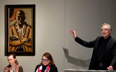 Auctioneer Markus Krause gestures in front of the painting 'Selbstbildnis gelb-rosa' (self-portrait yellow-rose) by German painter Max Beckmann, as it is auctioned in Berlin, Germany, December 1, 2022. (AP Photo/Michael Sohn)