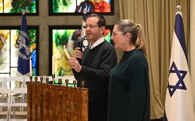 President Isaac Herzog lights the first candle of Hanukkah alongside his wife, Michal, at the President's Residence on December 18, 2022. (Haim Zach/GPO)