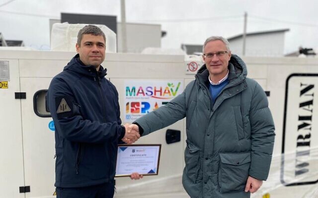 Israeli Ambassador to Ukraine Michael Brodsky (right) shakes hands with a Ukrainian official in front of a donated generator on December 20, 2022. (Israeli Embassy)