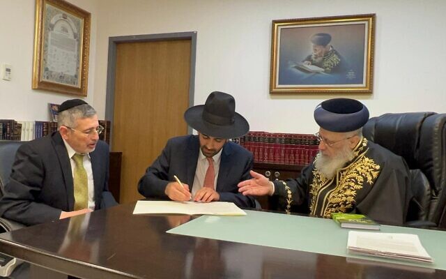 Incoming Religious Services Minister Michael Malkieli signs an order delaying the implementation of a kashrut reform as Sephardi Chief Rabbi Yitzhak Yosef, right, watches, in Malkieli's office in the Knesset on December 29, 2022. (Courtesy: Michael Malkieli's office)