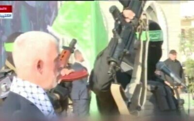 A masked member of Hamas holds up the supposed weapon of slain Israeli soldier Hadar Goldin, as the terror group's Gaza leader Yahya Sinwar looks on during a rally, December 14, 2022 (Video screenshot)