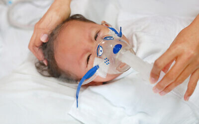 A sick baby with an inhalation mask to treat Respiratory Syncytial Virus (RSV) on a hospital bed. (GOLFX vis iStock by Getty Images)