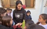 Children at the Bi'ne B elementary school near Deir el-Asad in northern Israel crowd around an iguana, November 28, 2022. (Sue Surkes/Times of Israel)