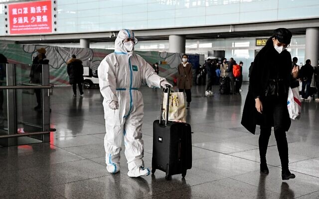 A passenger, wearing a personal protective equipment, walks at the arrival area at the Capital International Airport in Beijing on January 8, 2023. (Noel CELIS / AFP)