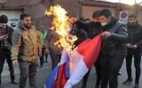 Demonstrators burn a French flag during a protest against cartoons of the Islamic Republic's Supreme Leader Ayatollah Ali Khamenei published by French satirical weekly Charlie Hebdo, outside the French embassy in Iran's capital Tehran on January 8, 2023. (Atta Kenare/AFP)