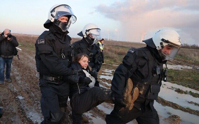 Police officers carry Swedish climate activist Greta Thunberg (C) out of a group of demonstrators and activists in Erkelenz, western Germany, on January 17, 2023, as demonstrations continue against a coal mine extension in the nearby village of Luetzerath (Photo by Christoph Reichwein / dpa / AFP)