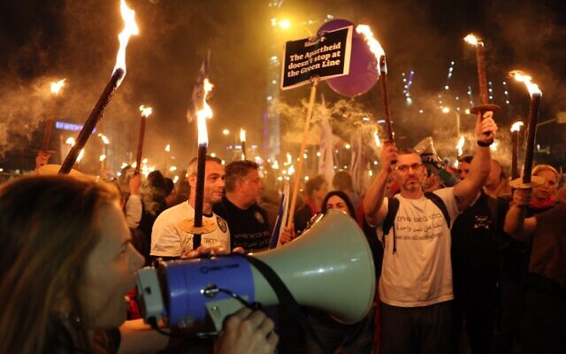 Israeli protesters carry torches during a rally against Prime Minister Benjamin Netanyahu's new government, in Tel Aviv on January 21, 2023. (Jack Guez/AFP)