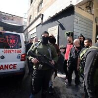 Palestinian gunmen and civilians gather around an ambulance following a raid by Israeli troops on the West Bank's Jenin refugee camp, January 26, 2023. (JAAFAR ASHTIYEH / AFP)