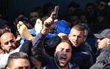 A man fires his gun into the air as Palestinians carry the body of one of the 9 reported victims killed during an Israeli raid on the West Bank's Jenin refugee camp, as they begin his funeral procession in the city of the same name on January 26, 2023. (Jaafar Ashtiyeh/AFP)