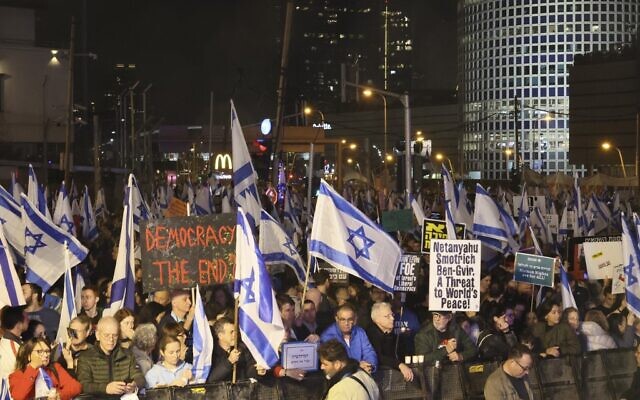 Israelis hold placards and wave flags in Tel Aviv on January 28, 2023 during a protest against controversial government plans to give lawmakers more control of the judicial system. (Jack Guez/AFP)