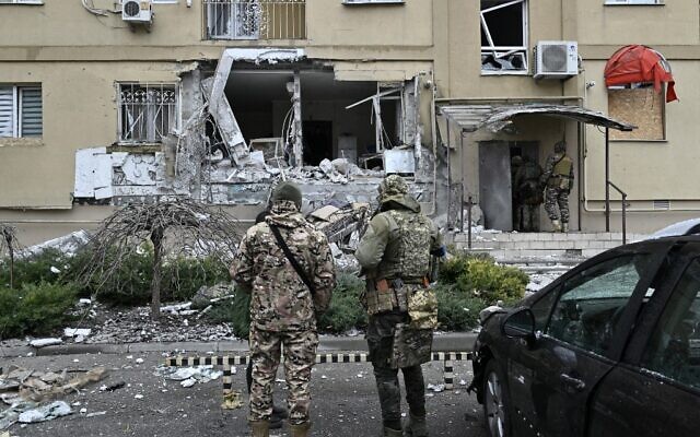 Ukrainian policemen stand in front of a damaged residential building after a Russian shelling in Kherson, southern Ukraine, on January 29, 2023. (Genya SAVILOV / AFP)