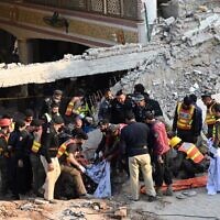 Rescue workers carry the remains of victims from the debris of a damaged mosque after a blast inside the police headquarters in Peshawar on January 30, 2023. (Abdul Majeed/AFP)