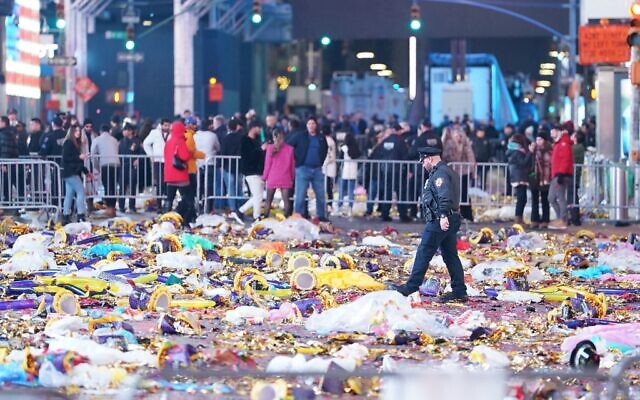 A police officer walks through garbage left behind by revelers at Times Square after the New Year celebrations on January 1, 2023 in New York City. (David Dee Delgado/Getty Images/AFP)