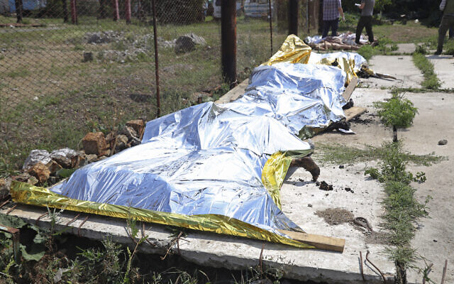 Investigators examine bodies of Ukrainian military prisoners at a prison in Olenivka, in an area controlled by Russian-backed separatist forces, eastern Ukraine, on July 29, 2022. (AP Photo)