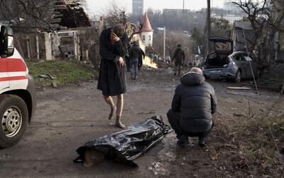 A man reacts next to the body of his wife, killed during a Russian attack in Kyiv, Ukraine, Dec. 31, 2022. (AP Photo/Roman Hrytsyna)