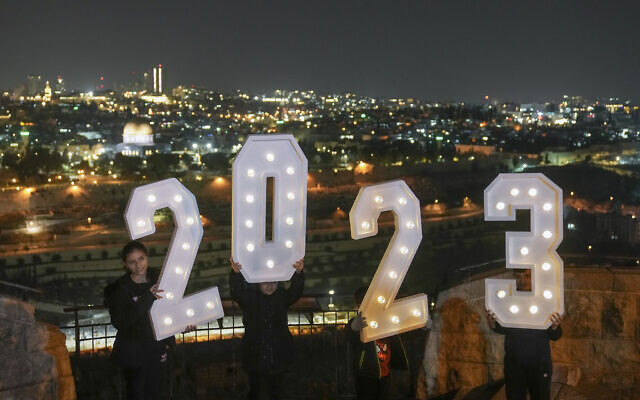 People pose for pictures with a 2023 installation as they celebrate the New Year's eve at Mount of Olives overlooking Jerusalem's Old City, December 31, 2022. (AP Photo/Mahmoud Illean)
