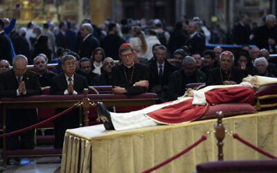 The body of late Pope Emeritus Benedict XVI, his head resting on a pair of crimson pillows, lying in state in St. Peter's Basilica at The Vatican, January 4, 2023. (Antonio Calanni/AP)