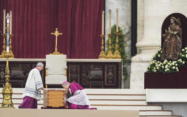 Archbishop Georg Ganswein kneels by the coffin of late Pope Emeritus Benedict XVI after it's brought to St. Peter's Square for a funeral mass at the Vatican, January 5, 2023. (Alessandra Tarantino/AP)