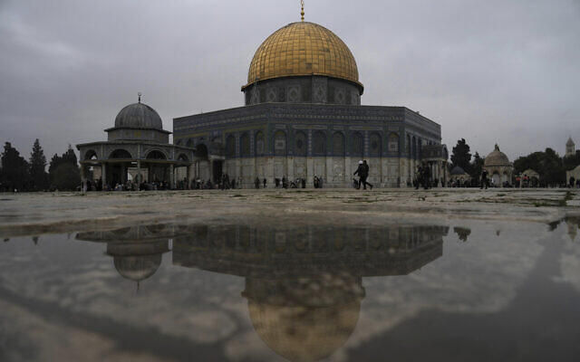 The Dome of the Rock Mosque is reflected in rainwater as worshippers gather for Friday prayers on a cold, rainy day at the Al-Aqsa Mosque compound in the Old City of Jerusalem, January 6, 2023. (AP Photo/ Mahmoud Illean)
