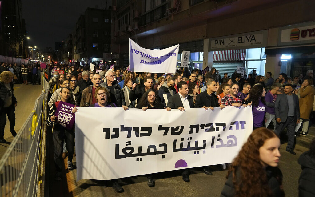 Lawmakers Ayman Odeh, center right, Mossi Raz, second from right, and Ofer Cassif, right, march behind a banner reading "This is our home," in Hebrew and Arabic in Tel Aviv on Saturday, January 7, 2023. (AP/ Tsafrir Abayov)