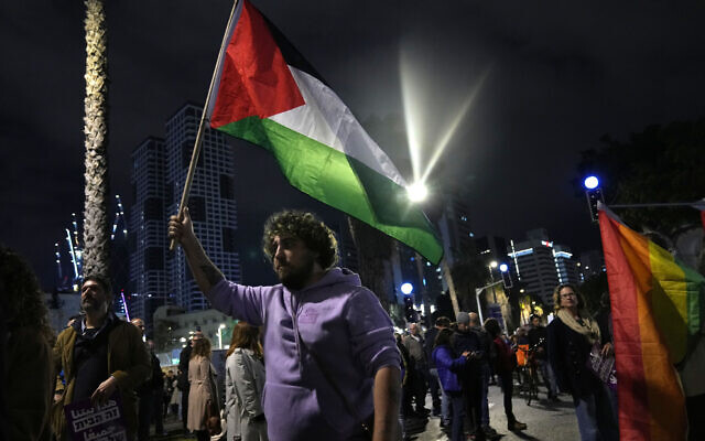 A protester holds a Palestinian flag in Tel Aviv at a demonstration against Prime Minister Benjamin Netanyahu's new government, January 7, 2023. (AP Photo/ Tsafrir Abayov)