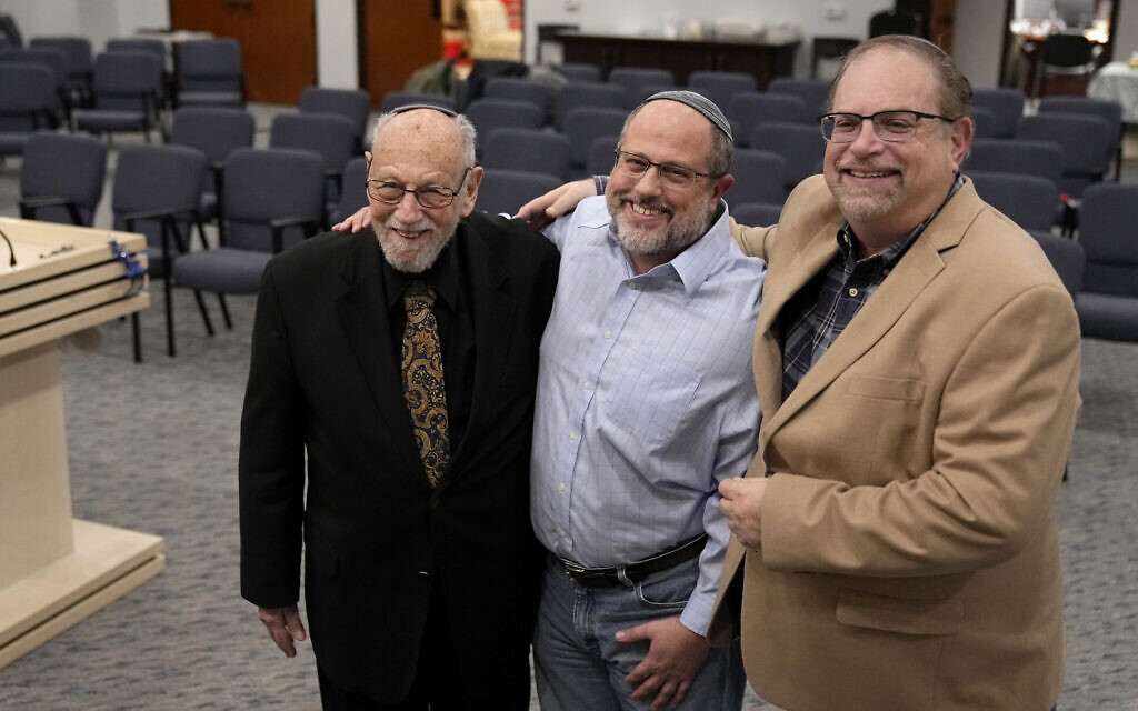 In this December 22, 2022, photo, Lawrence Schwartz, left, Shane Woodward, center, and Jeff Cohen, right, smile as they pose for a photo inside Congregation Beth Israel in Colleyville, Texas. (AP Photo/Tony Gutierrez)
