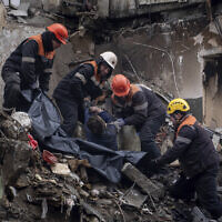 Rescue workers transfer the body of a man killed in a Russian missile strike on an apartment building into a plastic bag in the southeastern city of Dnipro, Ukraine, Monday, Jan. 16, 2023. (AP Photo/Evgeniy Maloletka)