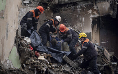 Rescue workers transfer the body of a man killed in a Russian missile strike on an apartment building into a plastic bag in the southeastern city of Dnipro, Ukraine, Monday, Jan. 16, 2023. (AP Photo/Evgeniy Maloletka)