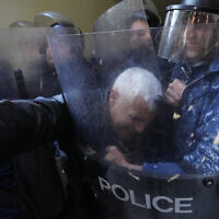 Anti-government protesters scuffle with riot police outside the Ministry of Justice, in Beirut, Lebanon on January 26, 2023. (AP Photo/Hassan Ammar)