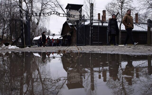 People walk next to the 'Arbeit Macht Frei' (Work Sets You Free) gate at the former Nazi German concentration and extermination camp Auschwitz-Birkenau in Oswiecim, Poland, Thursday, Jan. 26, 2023 (AP Photo/Michal Dyjuk)