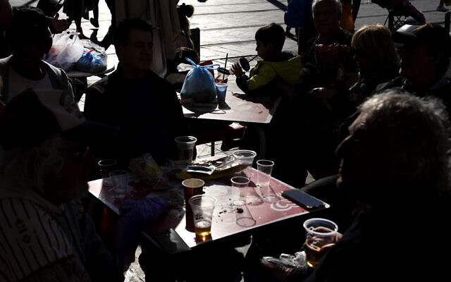 People drink in disposable plastic glass at Mahane Yehuda market in Jerusalem, January 20, 2023. (Oded Balilty/AP)