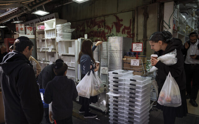 People buy disposable plastic dishes at Mahane Yehuda market in Jerusalem, January 20, 2023. (Oded Balilty/AP)