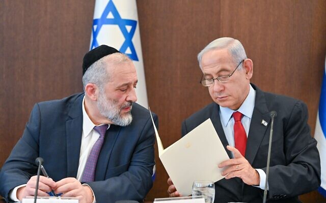 Prime Minister Benjamin Netanyahu (left) reads a letter to Shas chair Aryeh Deri, informing Deri that he must remove him from ministerial office, at the weekly cabinet meeting in Jerusalem, January 22, 2023. (Kobi Gideon/GPO)