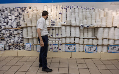A man shops for disposable plastic tableware in Osher Ad Supermarket in Givat Shaul, Jerusalem, October 27, 2021, shortly after new taxes on disposables went into effect in Israel. (Yonatan Sindel/Flash90)