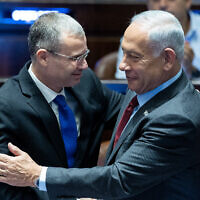 Benjamin Netanyahu, right, embraces Yariv Levin in the Knesset plenum on December 13, 2022. (Yonatan Sindel/Flash90)