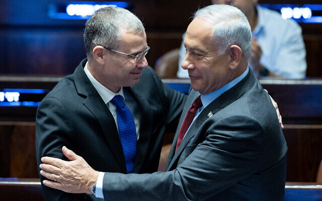 Benjamin Netanyahu, right, embraces Yariv Levin in the Knesset plenum on December 13, 2022. (Yonatan Sindel/Flash90)