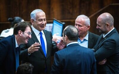 Benjamin Netanyahu speaks with other Likud MKs including Nir Barkat (back to camera) and Avi Dichter (right) in the Knesset plenum on December 28, 2022. (Olivier Fitoussi/Flash90)