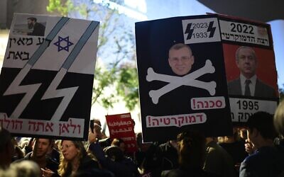 Placards blaming Prime Minister Benjamin Netanyahu for political violence and likening him, Justice Minister Yariv Levin and their government to Nazis, brandished at a Tel Aviv political protest, January 7, 2023. (Tomer Neuberg/Flash90)