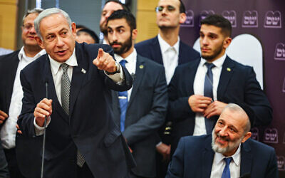 Prime Minister Benjamin Netanyahu speaks at a Shas party faction meeting at the Knesset, with Shas leader Aryeh Deri seated at his side, on January 23, 2023. (Yonatan Sindel/Flash90)